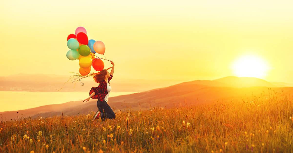 running with balloons in a field with sunshine to demonstrate authentic happiness